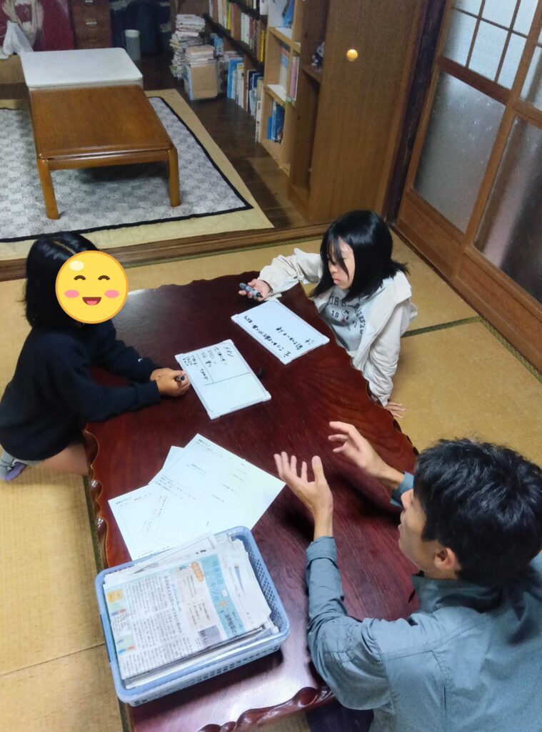 座卓で小さなホワイトボードに献立の案を書く子どもたちとスタッフ
