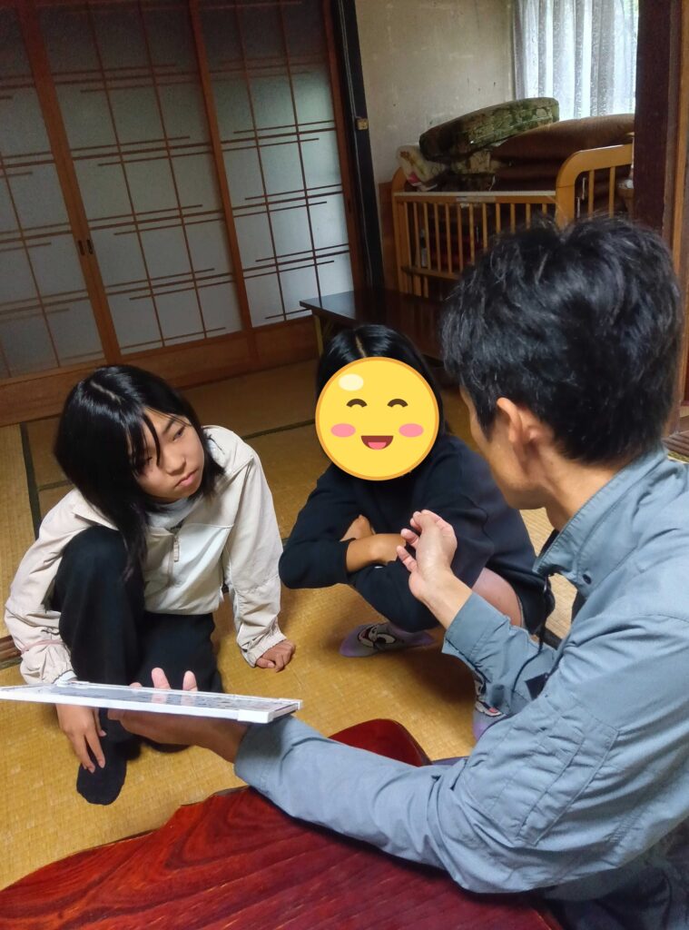 ホワイトボードの案を見せるスタッフと、話を聞く子どもたち