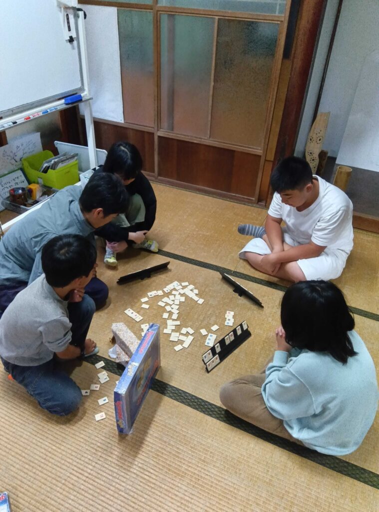 畳の上でボードゲームを囲む子どもたちとスタッフ