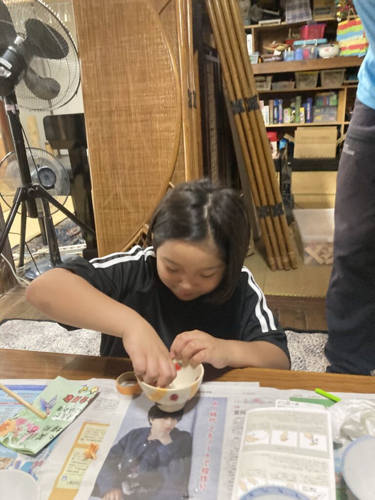 金継ぎ中の器に手を添える子ども