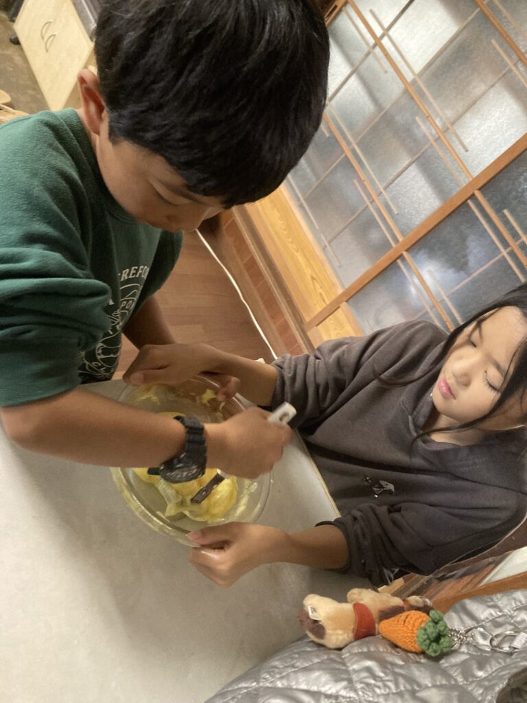 ボウルの中身を泡立て器で混ぜる子どもたち