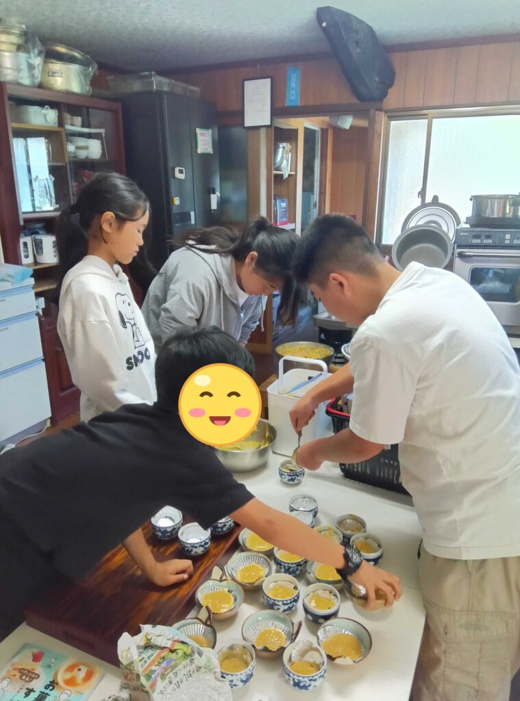 台所でカップケーキの生地を器に入れる子どもたちとスタッフ