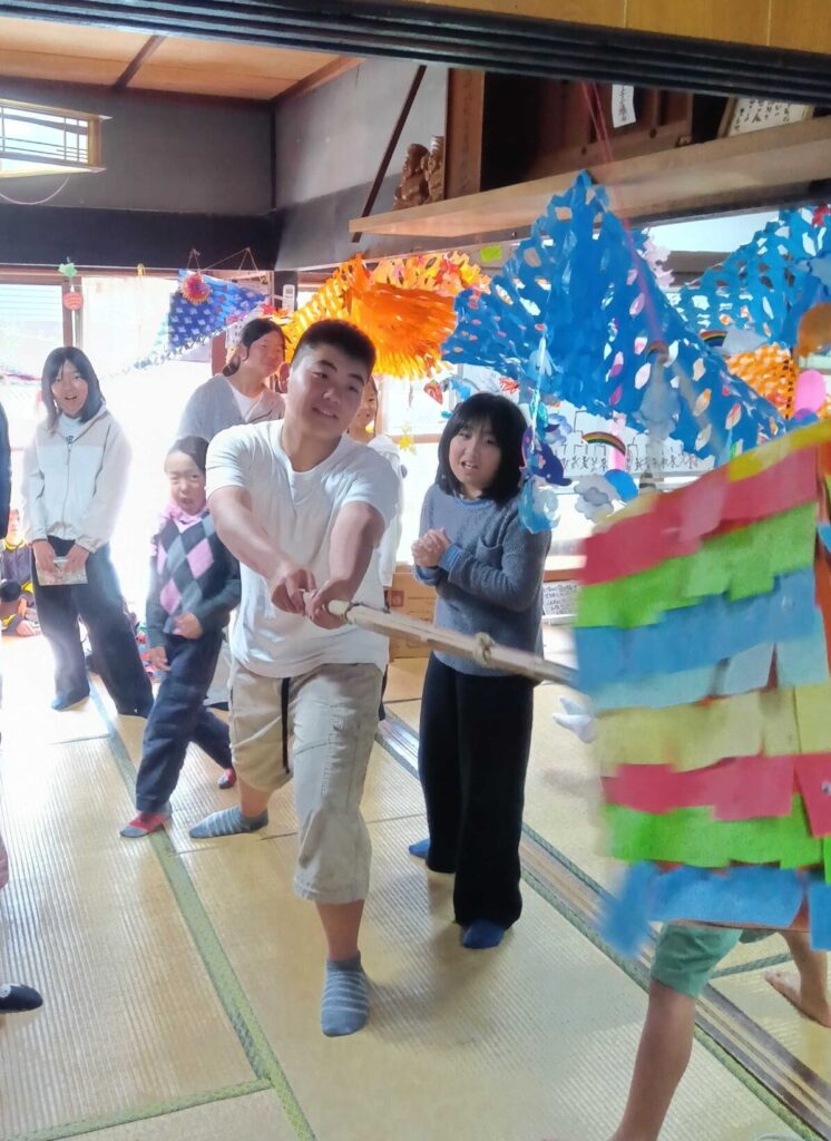 みんなが見守る中、ピニャータを棒でたたく子ども