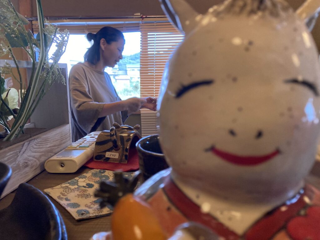 陶器の置物の向こうで展示の準備をする大人