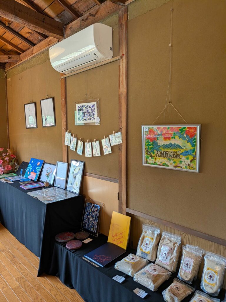 古民家の壁に絵が飾られ、作品やお米が並ぶいとう家さんの展示スペース